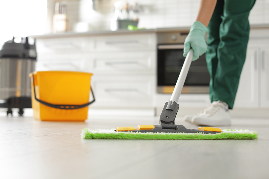 janitor cleaning floor with mop in kitchen